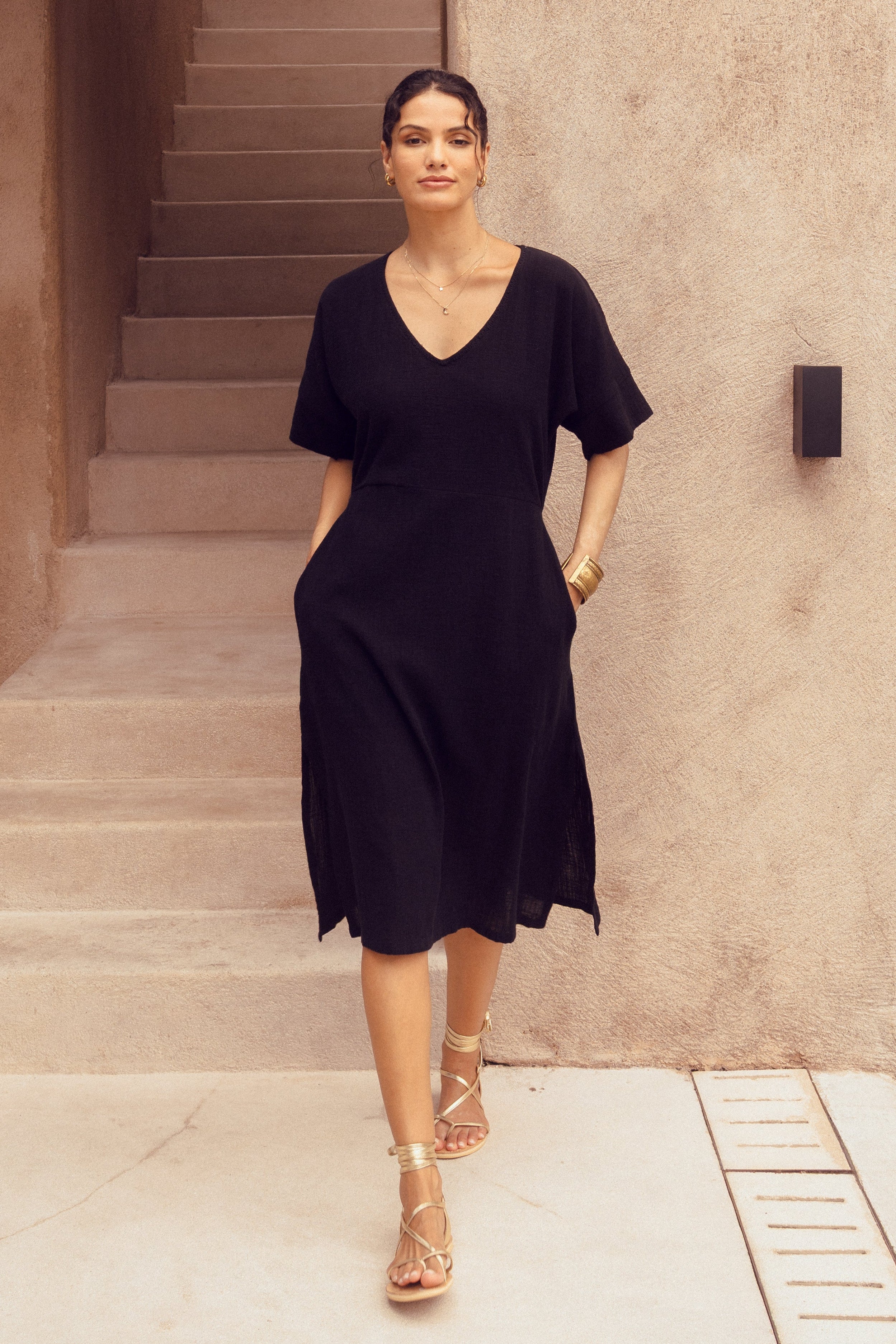 Woman in a black dress standing in front of a modern architectural building.