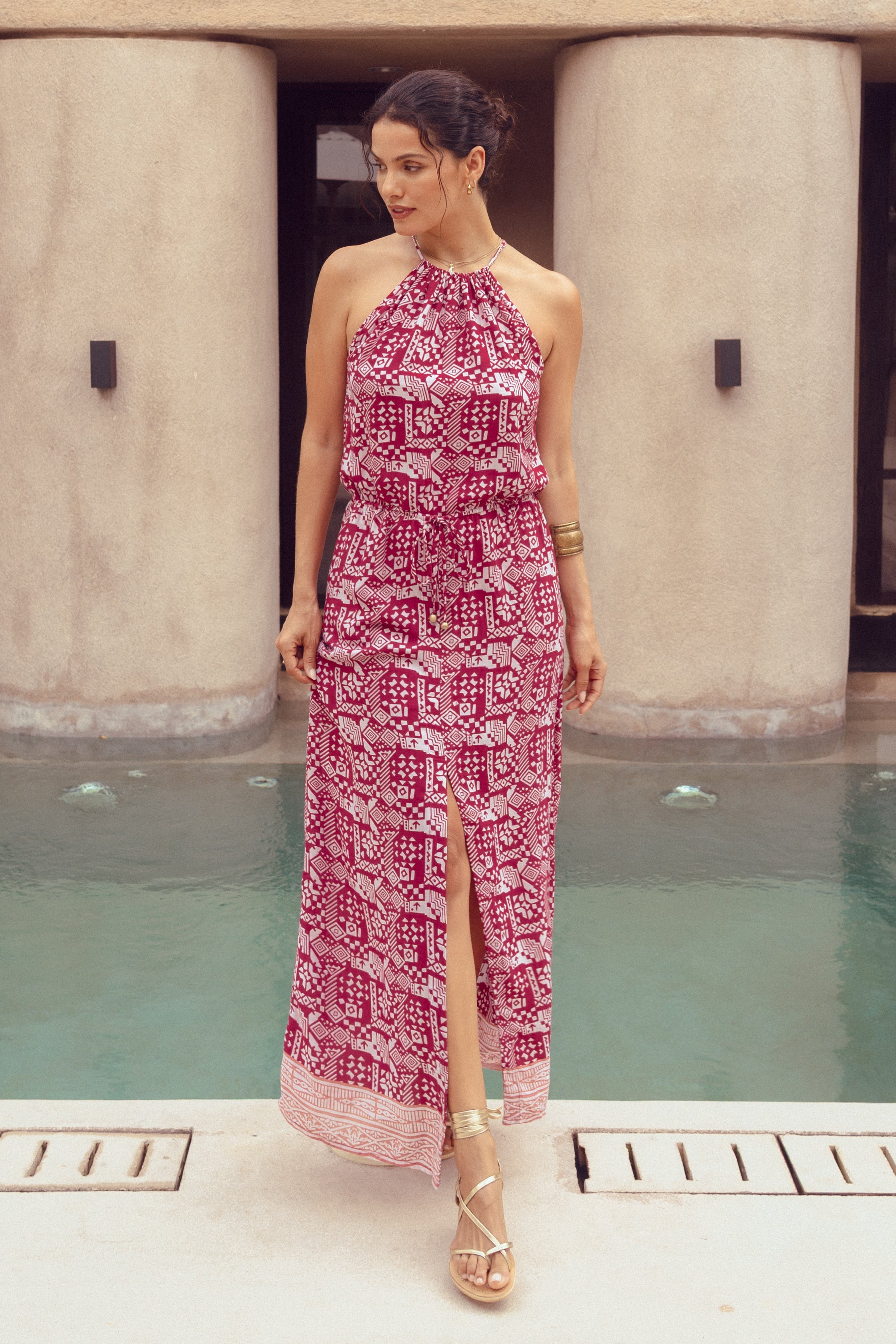 Woman in a pink dress standing by a pool with a building in the background