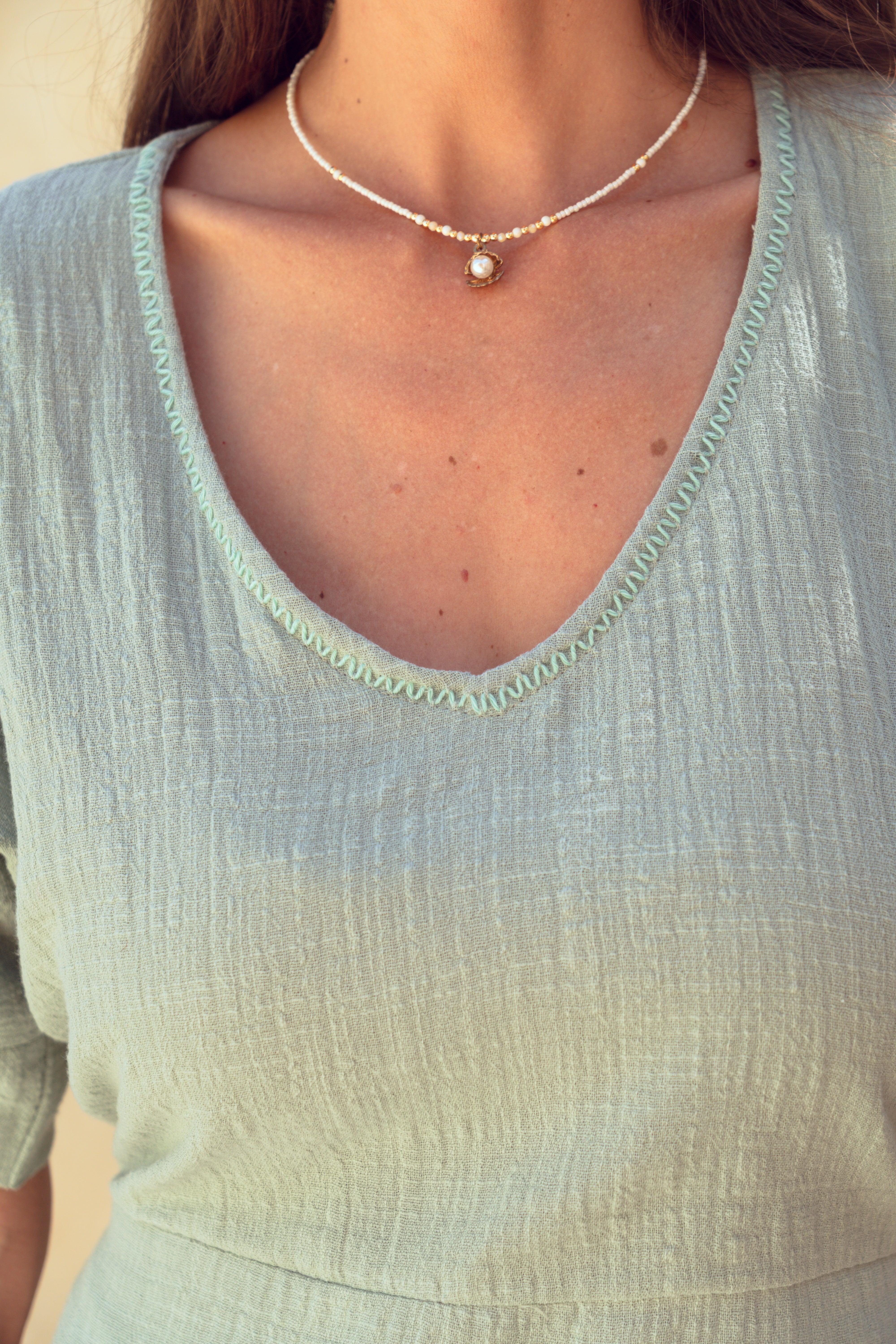 Close-up of a woman wearing a light green cotton dress with hand stitched neckline.
