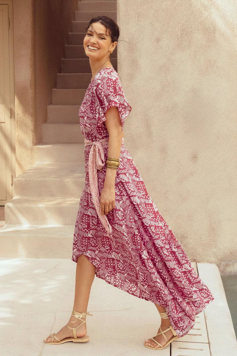 Woman in a pink floral dress standing on a staircase.