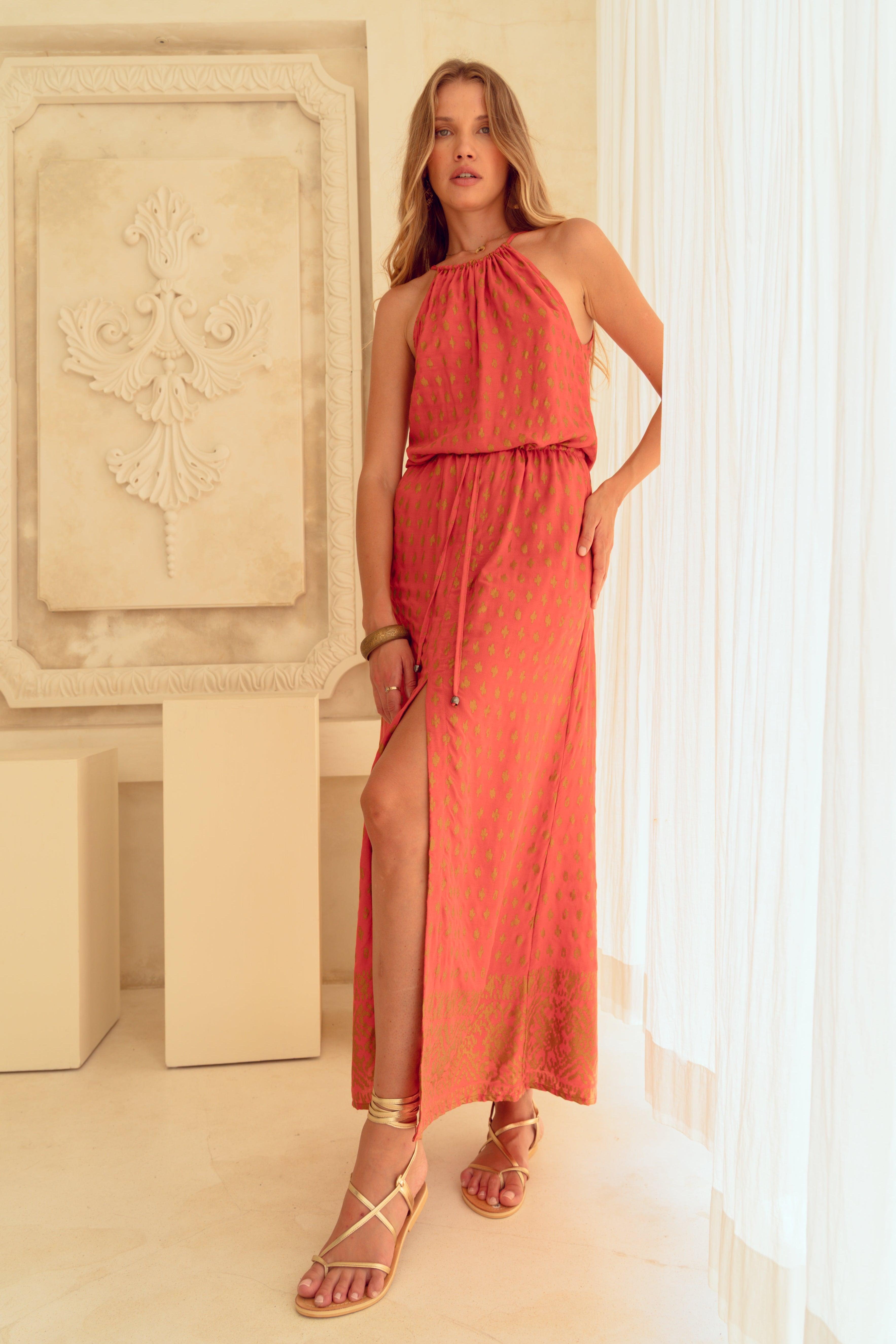 Woman in a coral dress standing in a room with architectural elements.