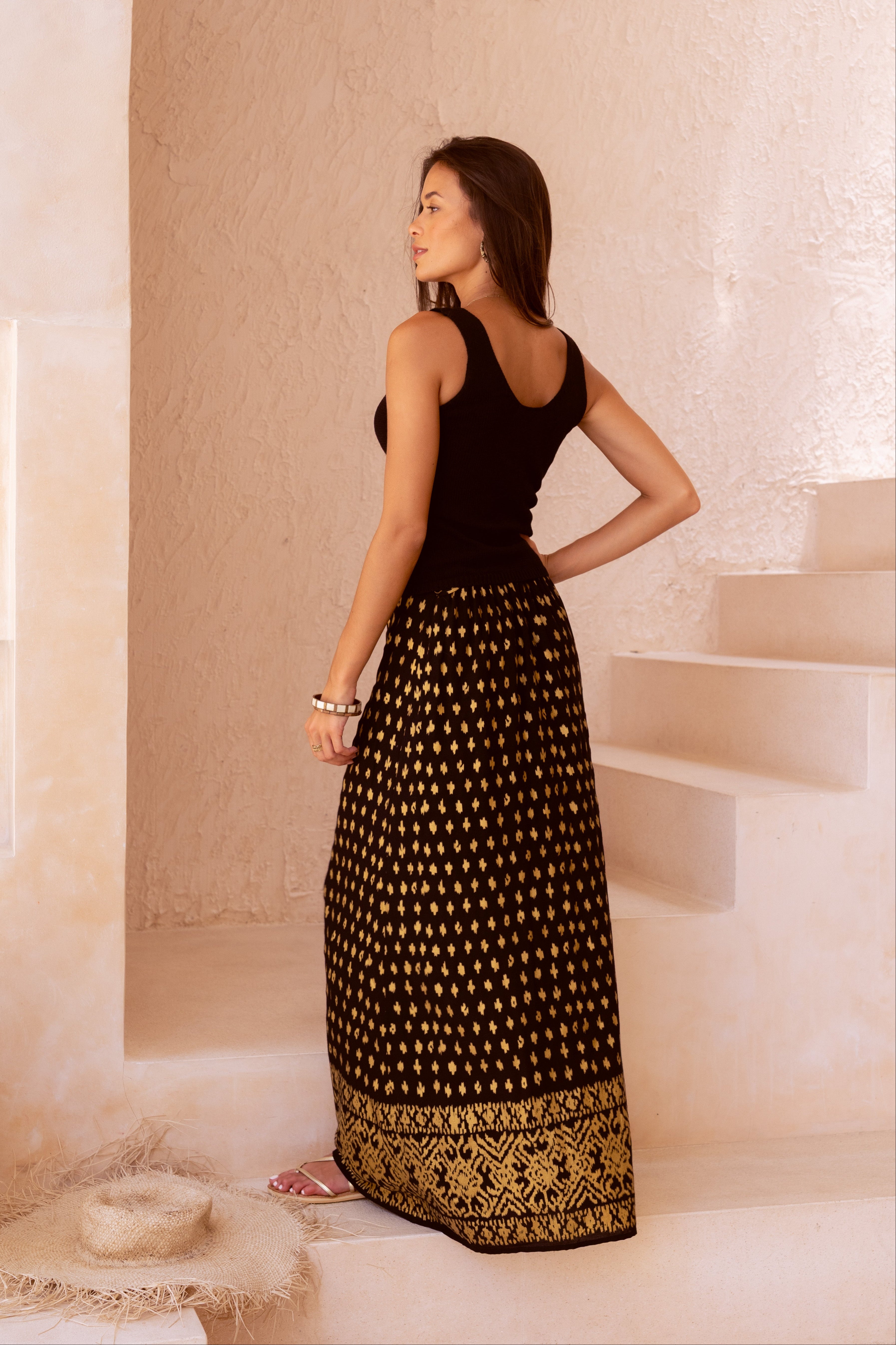 Mara black and gold maxi skirt standing on a staircase.